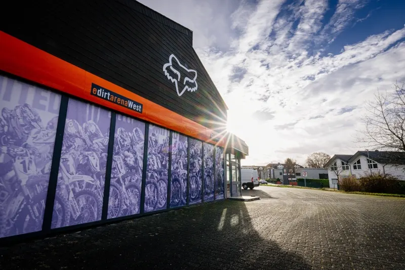 Au&szlig;enansicht der eDirtarena West mit Parkplatz und FOX-Logo an der Fassade