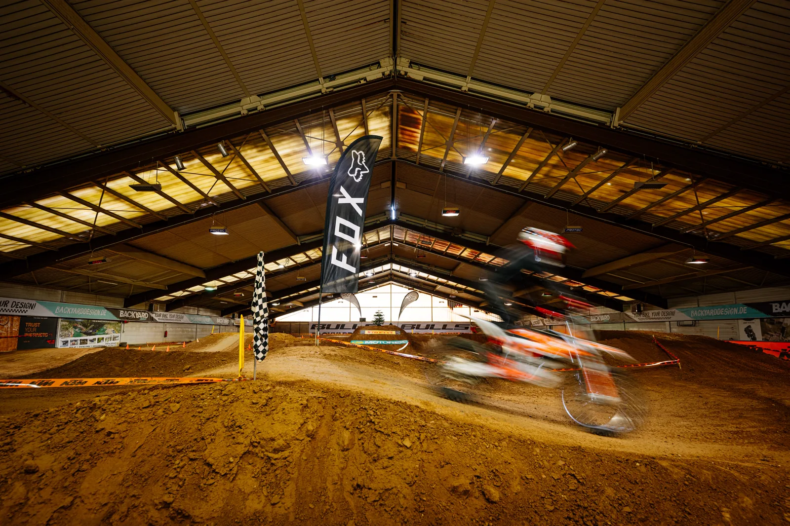 Übersicht der Indoor-Motocross-Strecke mit Sprunghügeln und Fox-Fahne