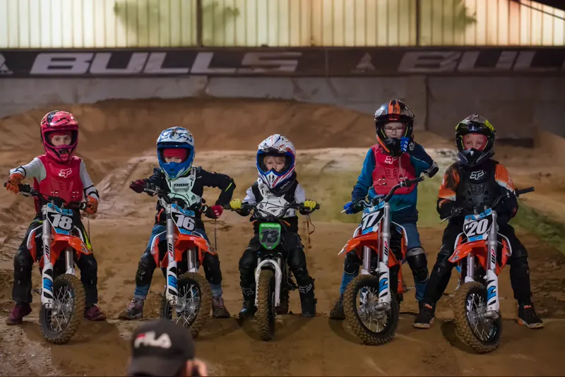 Fünf Kinder auf Elektro-Motorrädern an der Startlinie beim Motocross-Kindergeburtstag