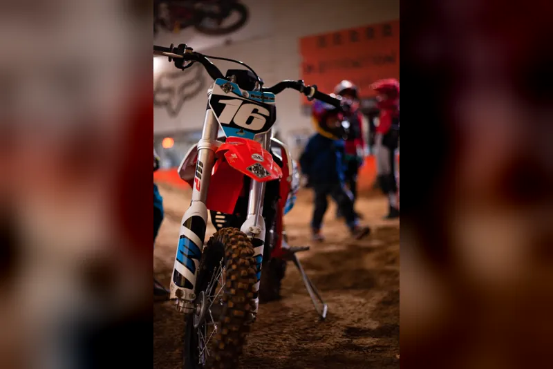 Kinder-Motocross-Motorrad mit Startnummer 76 von vorn, dahinter wartende Fahrer
