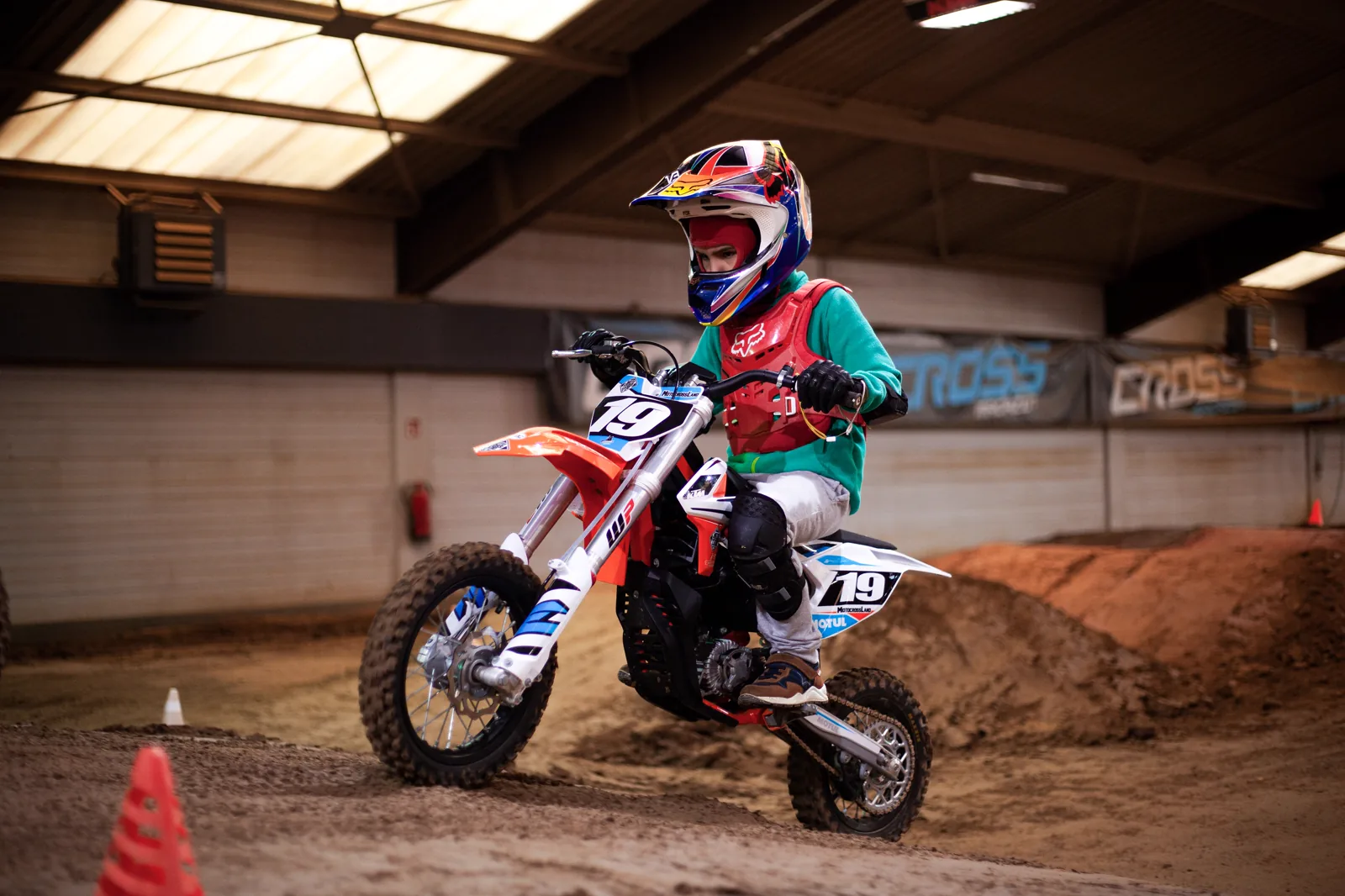 Kurventechnik im Kinderkurs Kind fährt auf einem Elektro-Motorrad durch eine Kurve der Indoor-Strecke