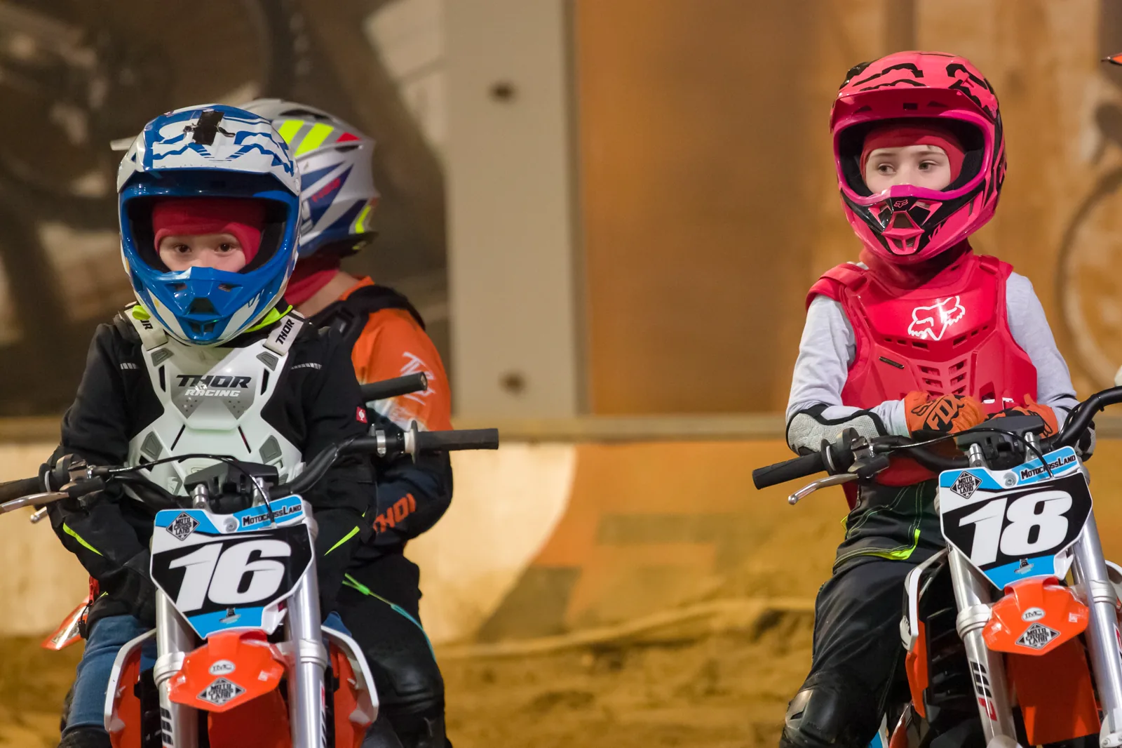 Zwei Kinder mit Helm und Protektoren auf ihren Motorrädern in Nahaufnahme
