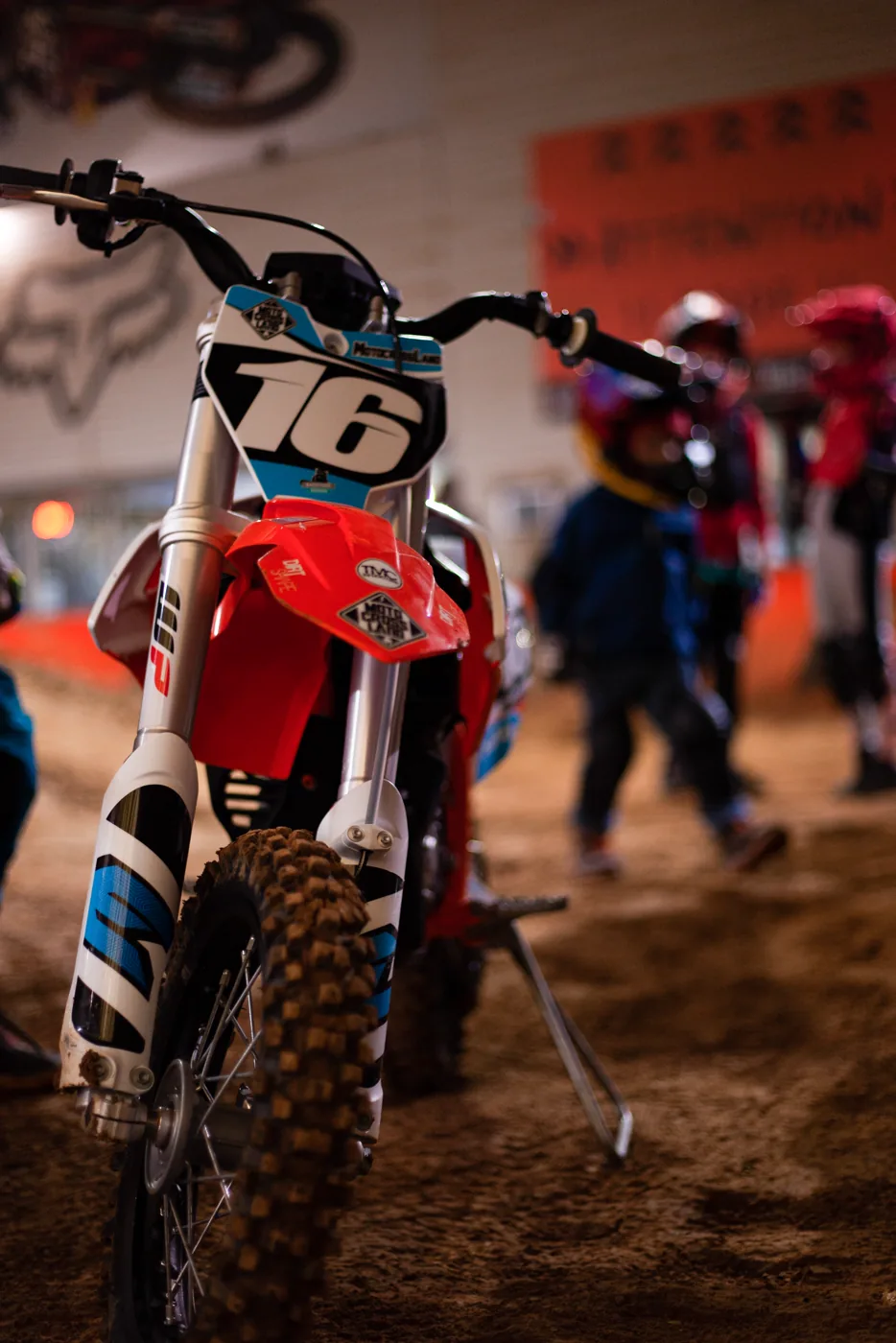 Kinder-Motocross-Motorrad mit Startnummer 76 von vorn, dahinter wartende Fahrer