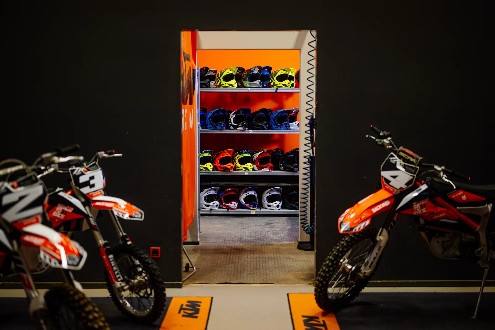Zwei KTM Freeride E neben dem Helmregal des Ausrüstungsverleihs